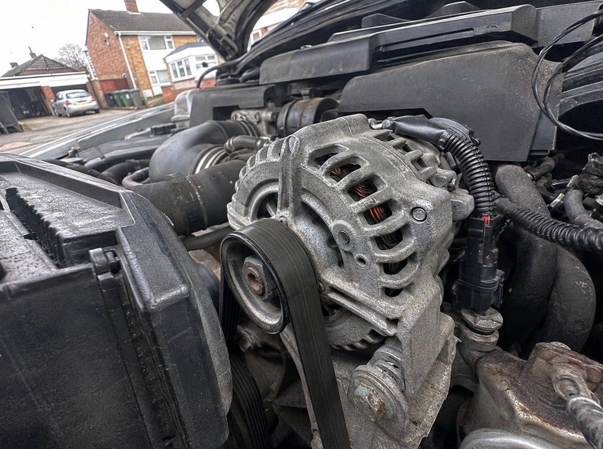 Mobile mechanic replacing an alternator on a car engine at a residential property in Coventry