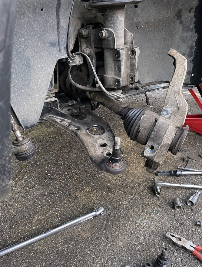 Mobile mechanic replacing a ball joint on a car suspension during a home visit in Coventry
