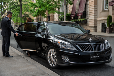 Person entering a black luxury sedan parked outside a building
