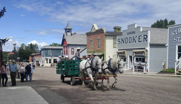 Horse-drawn cart on a western-style street with a crowd and buildings labeled “Snooker” and “Stage Stop”