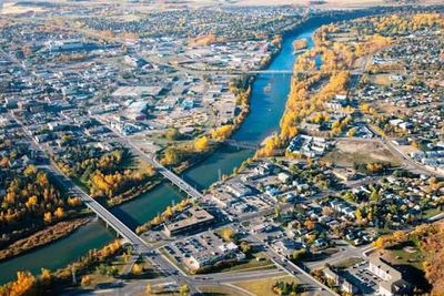 Aerial view of a city with a river running through it, bridges crossing, and autumn-colored trees along the banks