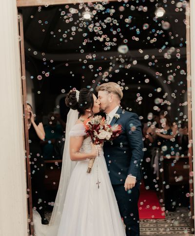 Bride and groom stepping out of a white vintage car at a grand venue