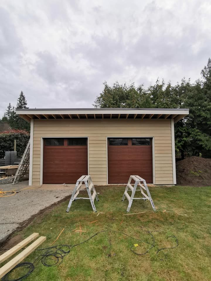 A garage with two garage doors is being built in a backyard.