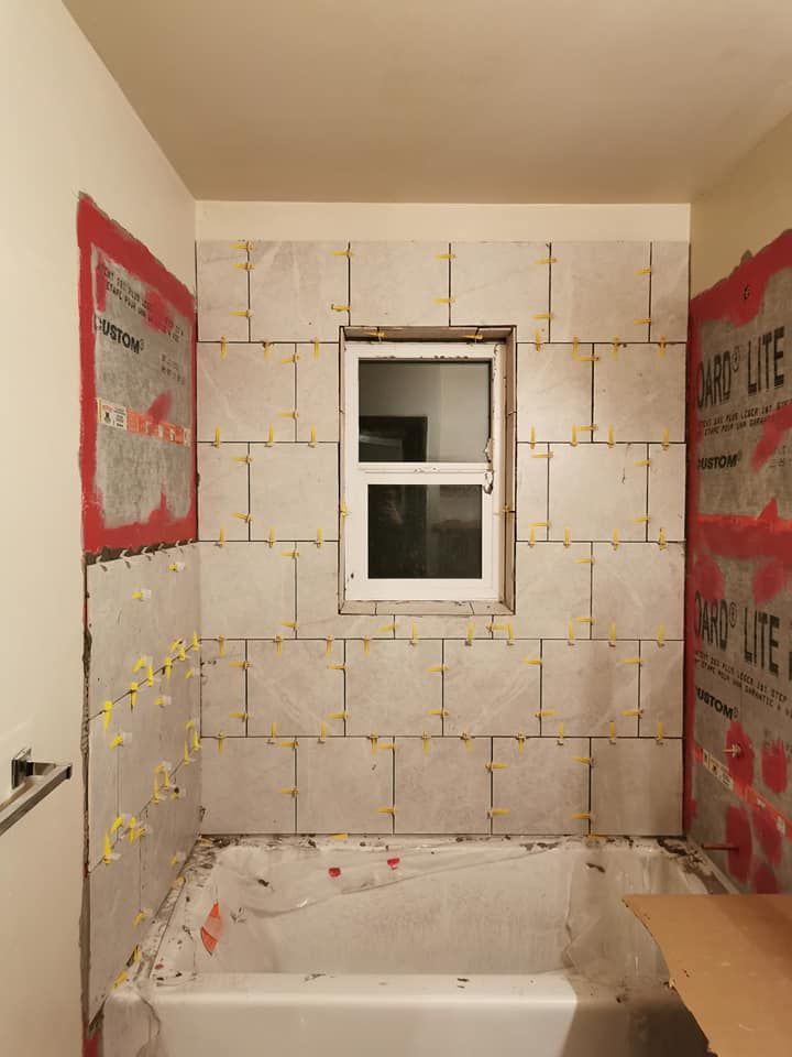 A bathroom with a tub and a window being remodeled.