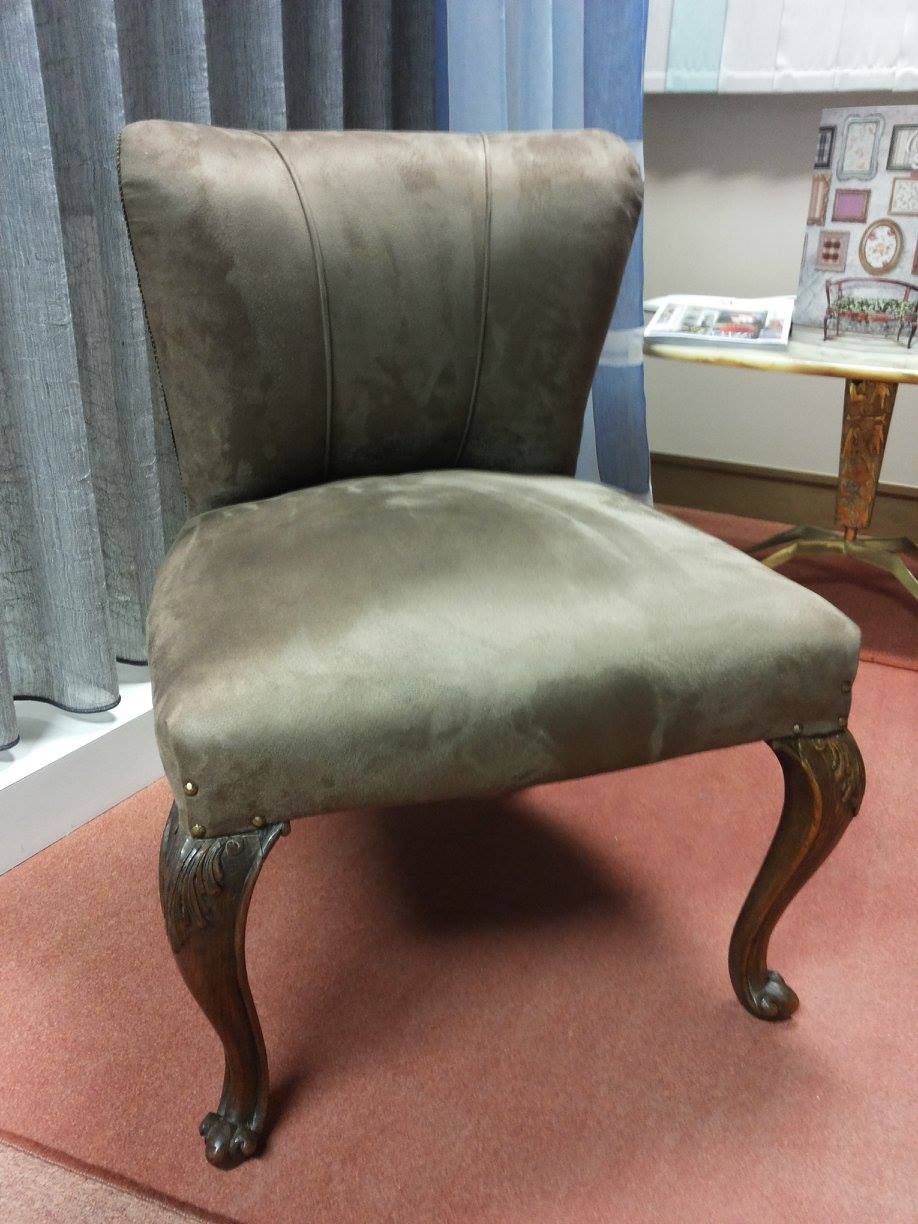 Sedia imbottita marrone con gambe in legno scuro intagliato, in una stanza.
