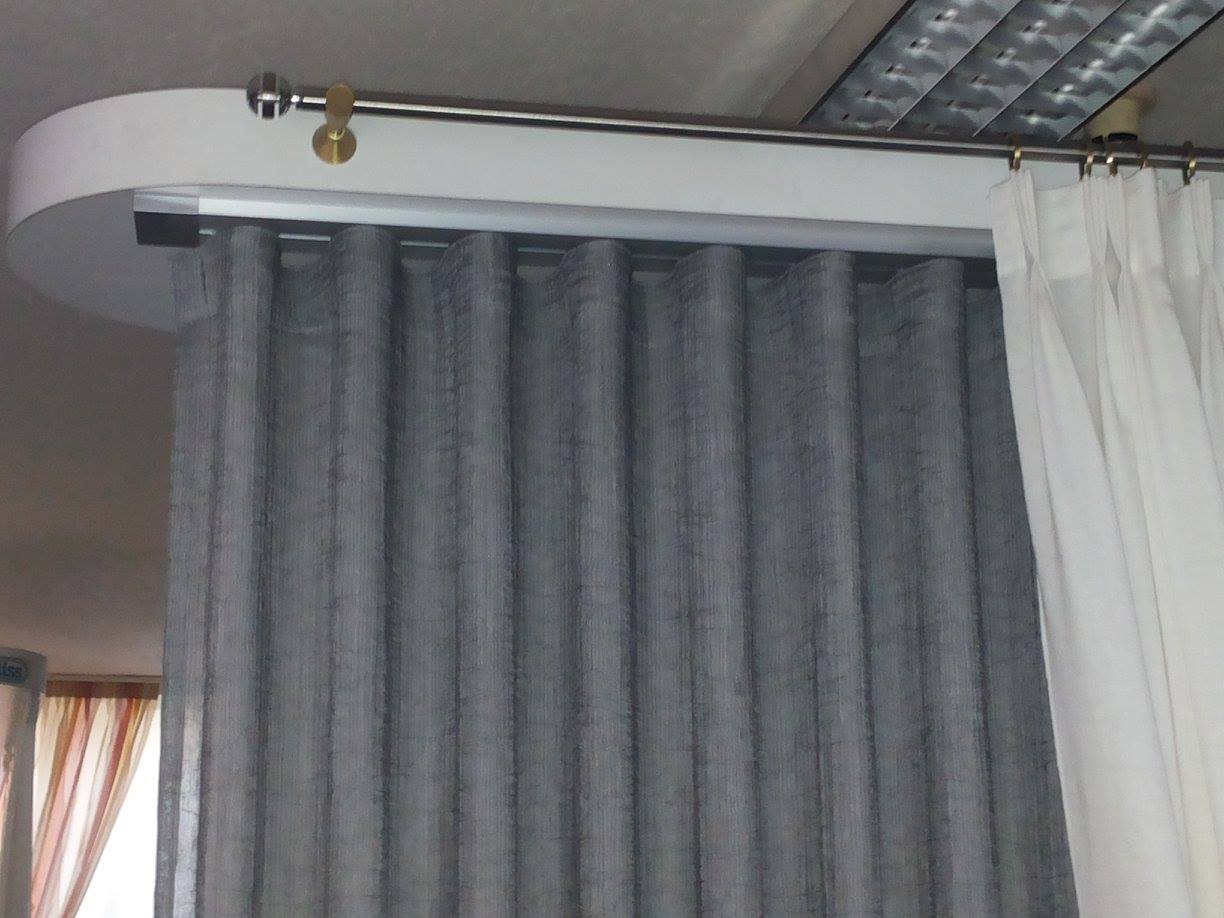 Tende appese a un drappeggio ovale bianco, tessuto grigio a sinistra e bianco a destra.