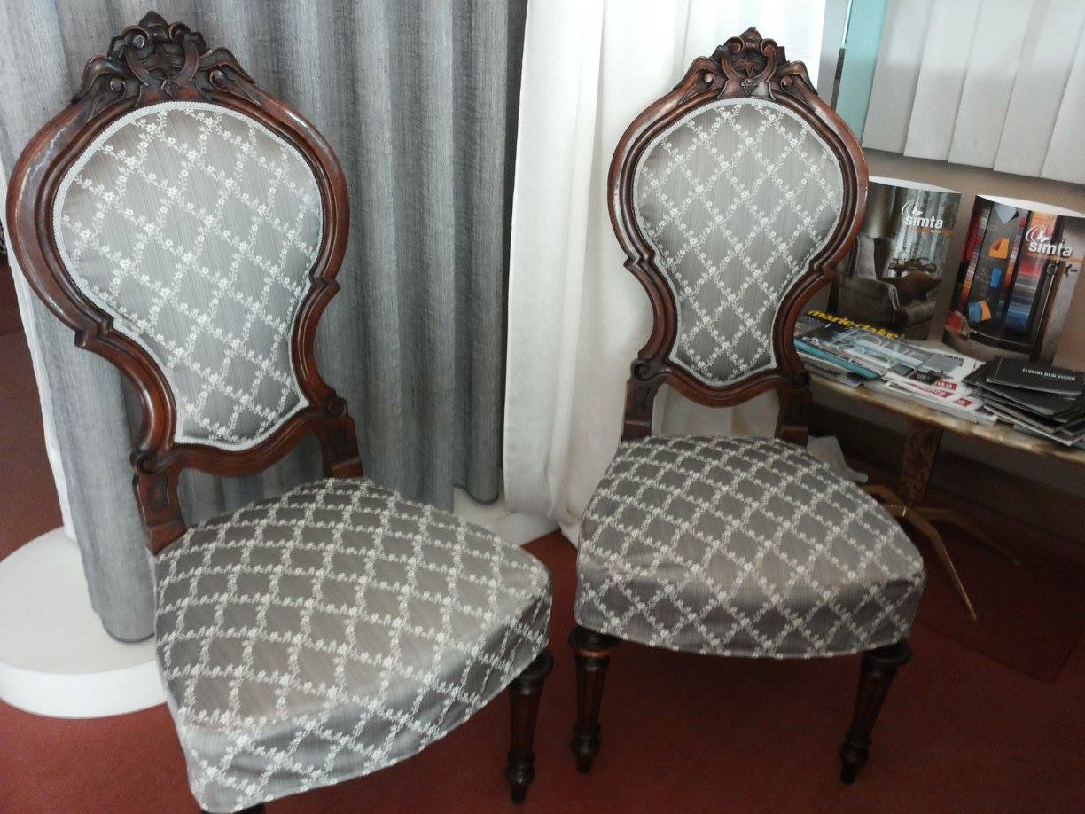 Due sedie decorate in legno scuro con rivestimento a fantasia grigia.