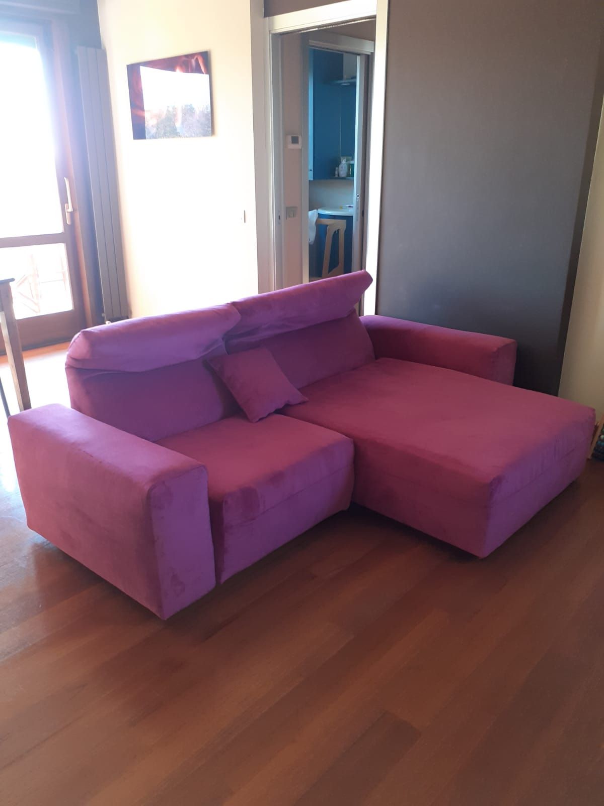 Divano componibile viola in una stanza con pavimento in legno.