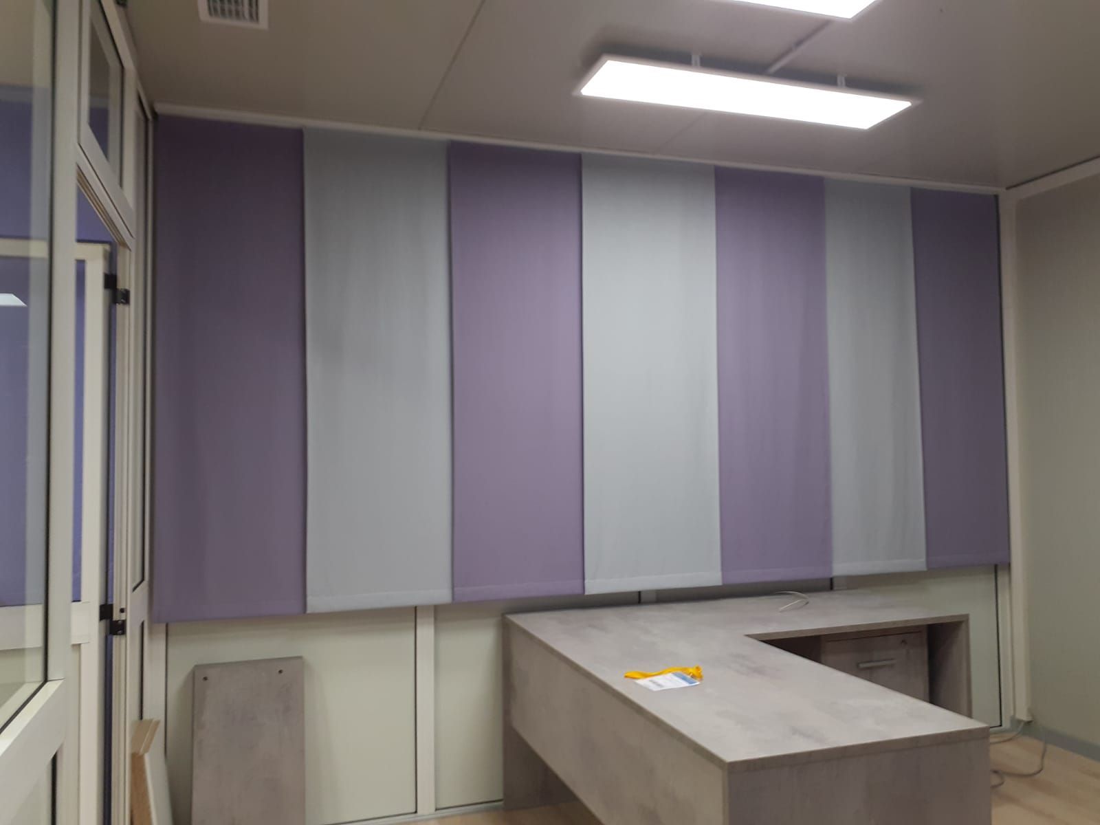 Parete dell'ufficio con pannelli alternati viola e grigi; scrivania di fronte.