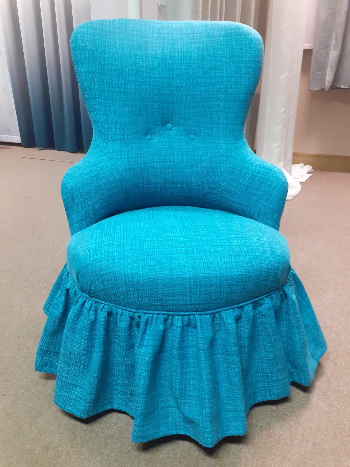 Poltrona da toeletta imbottita color turchese con gonna arricciata.