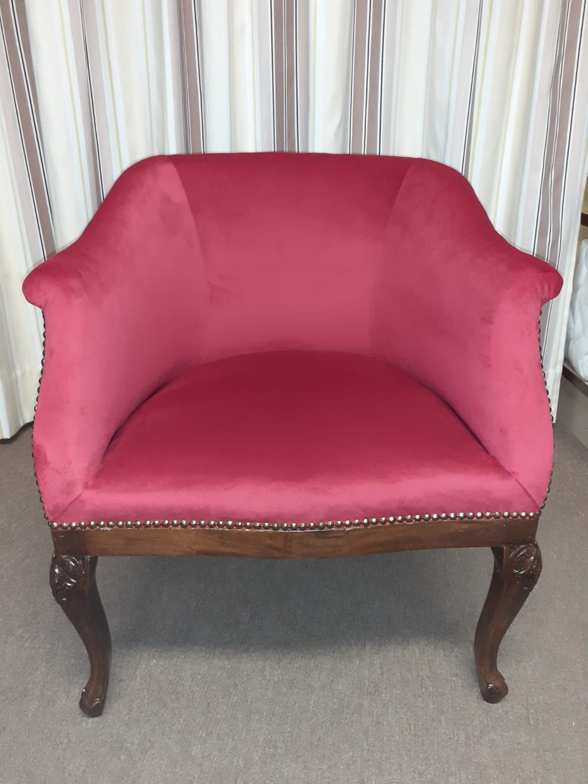 Poltrona in velluto rosa con finiture e gambe in legno, dettagli decorati.
