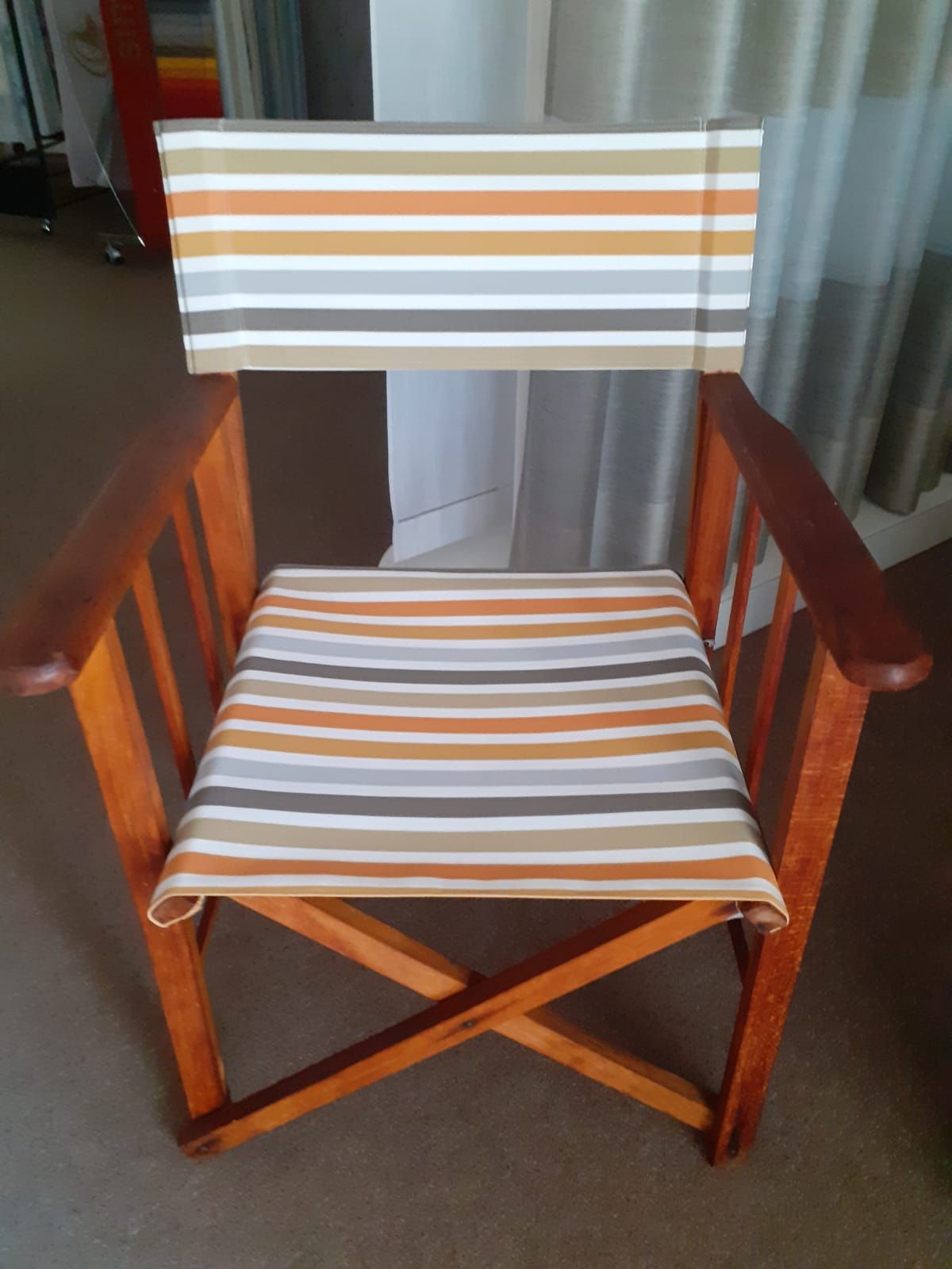 Sedia pieghevole in legno con seduta e schienale a righe color cuoio, marrone e grigio.