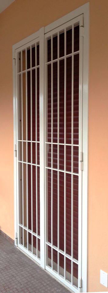 Cancello di sicurezza in metallo bianco su un muro color pesca accanto a una porta