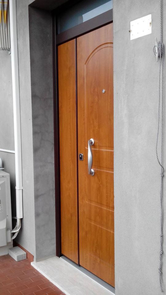 Porta di legno chiusa con maniglia argentata incastonata in un muro esterno grigio d'ingresso