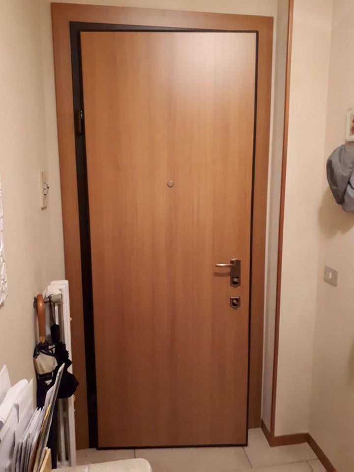 Porta interna di un appartamento con finitura in legno chiaro, vista da uno stretto corridoio.