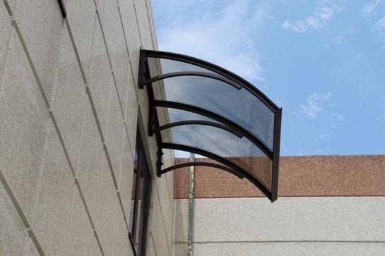 Tenda curva in vetro e metallo su un edificio beige sotto un cielo azzurro