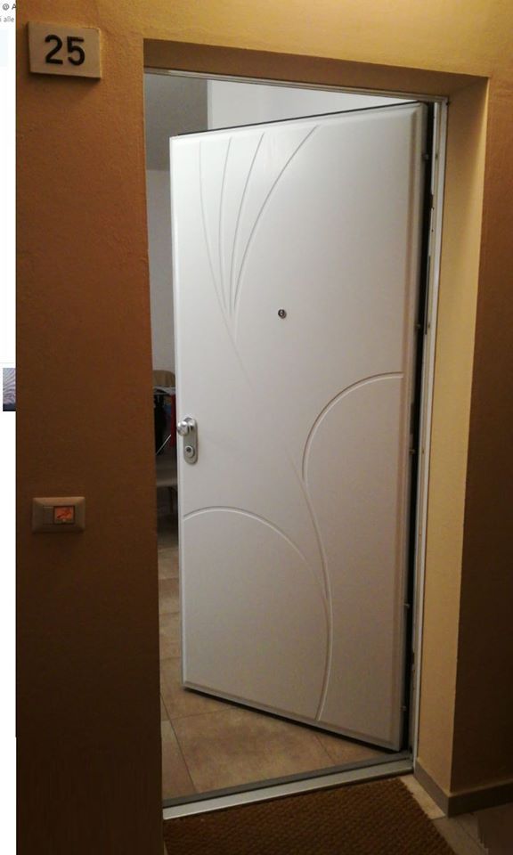 La porta bianca dell'appartamento si apre su un corridoio color beige, con il numero 25 sul muro.