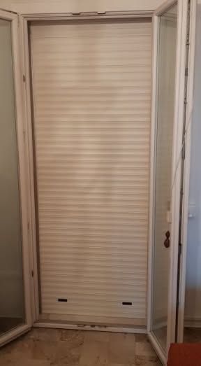 Una porta a soffietto bianca in un corridoio, parzialmente aperta tra due ante a specchio.