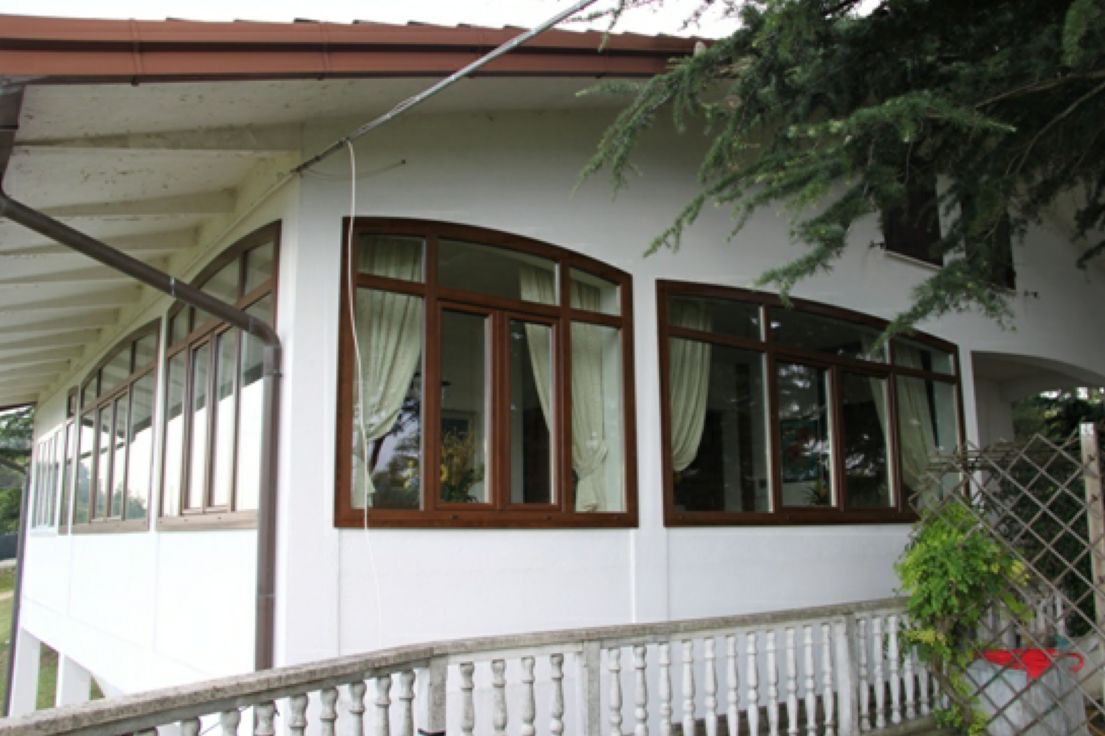 Esterno di una casa bianca con finestre incorniciate di marrone e un piccolo portico anteriore sotto una tettoia.