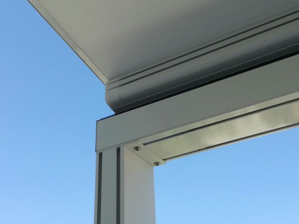 Primo piano dell'angolo di un edificio bianco con la cornice del tetto sullo sfondo di un cielo blu.