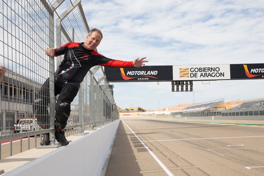 Racecar driver in black and red suit standing on a pit wall at MotorLand Aragón track