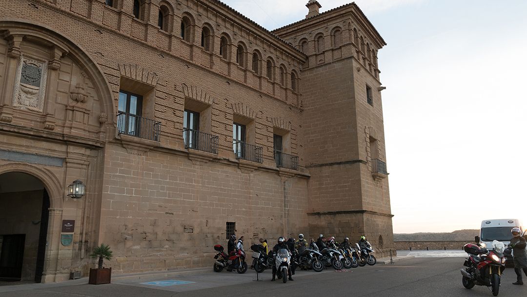 Historic brick fortress with tower, parked motorcycles, and a few people in a courtyard