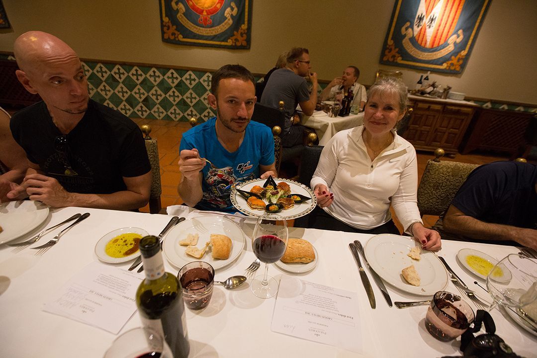 People seated at a restaurant table with plates of food, chatting over a meal.