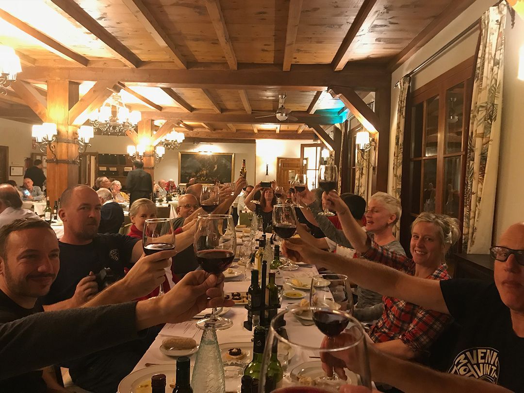 People raising wine glasses in a warm, rustic restaurant during a group dinner toast