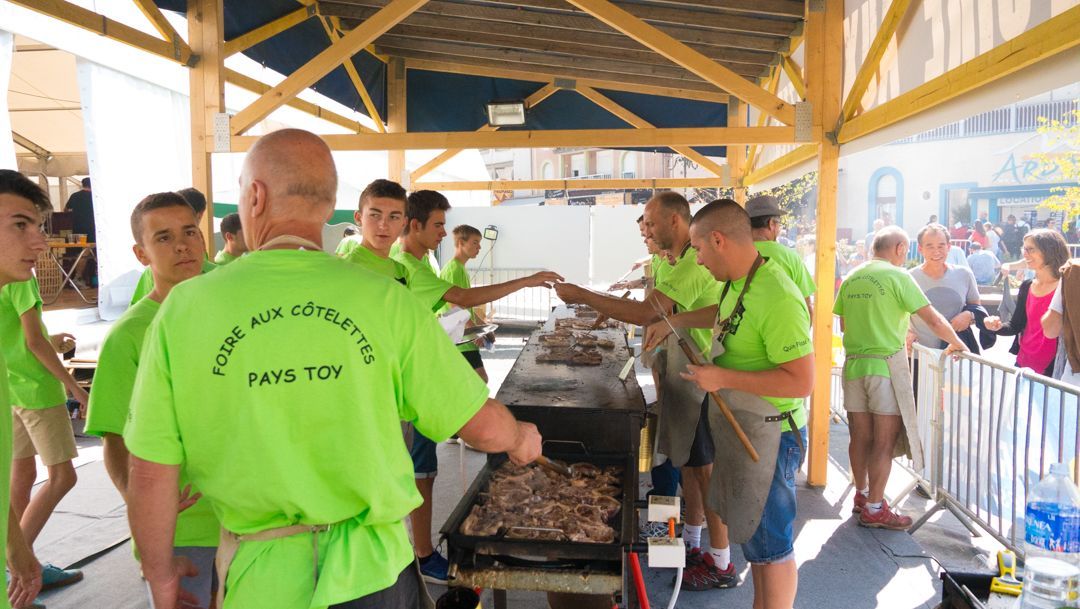 Workers in neon green shirts cooking meat at an outdoor pavilion barbecue