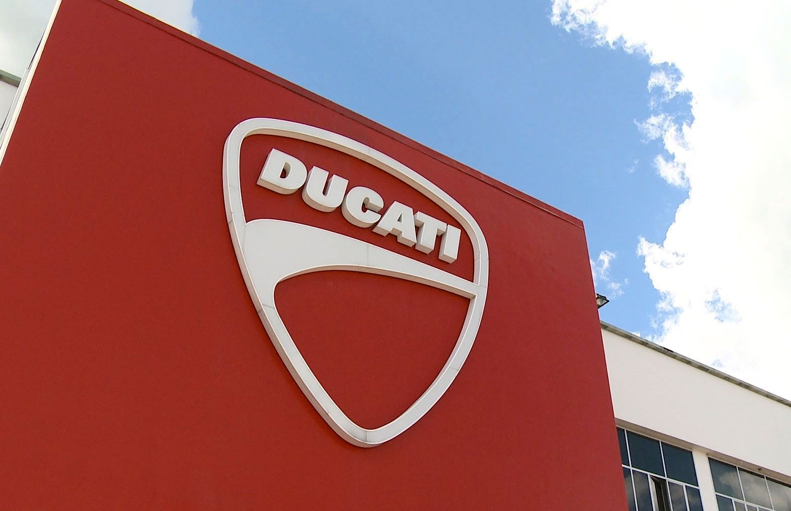 Ducati logo on a red building facade against a blue sky
