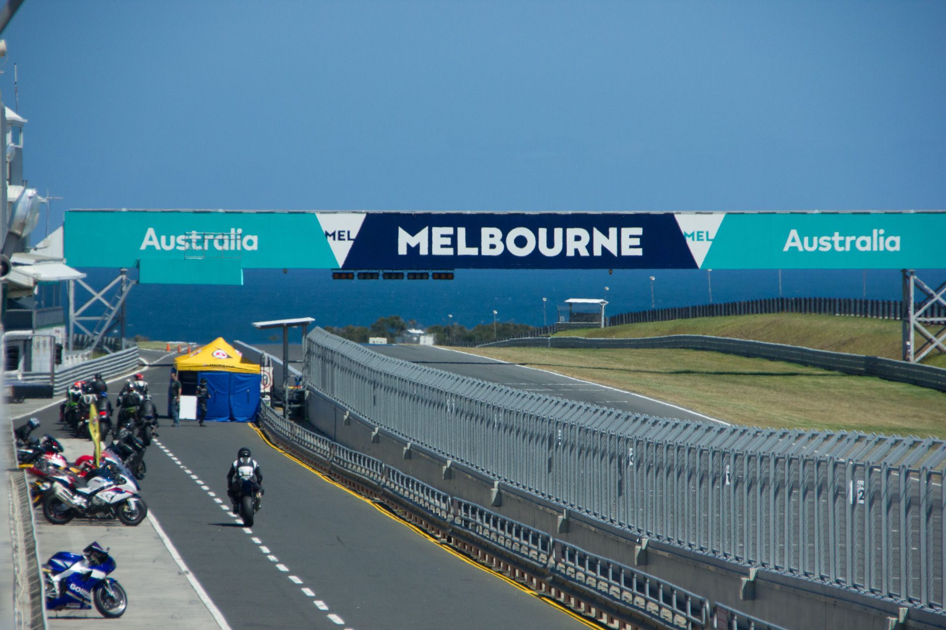 Motorbike on racetrack near Melbourne banner and pit lane under clear blue sky