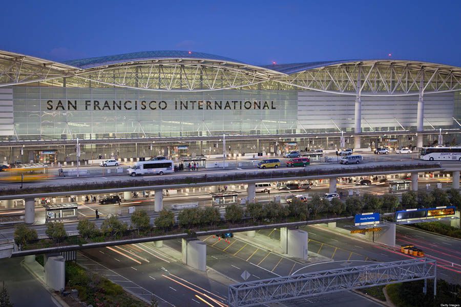 San Francisco International Airport terminal at dusk, with illuminated roadway and parked aircraft in front