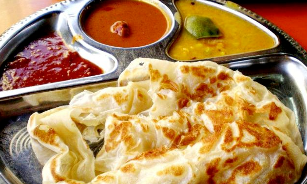 Naan bread served with three colorful curry dips on a metal tray