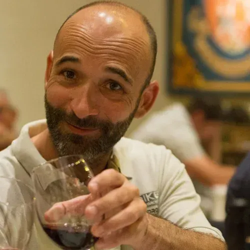 Smiling man raising a wine glass in a softly lit restaurant