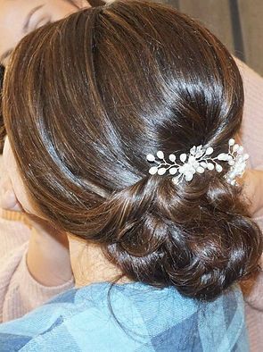 A woman is wearing her hair in a bun with a flower in her hair.