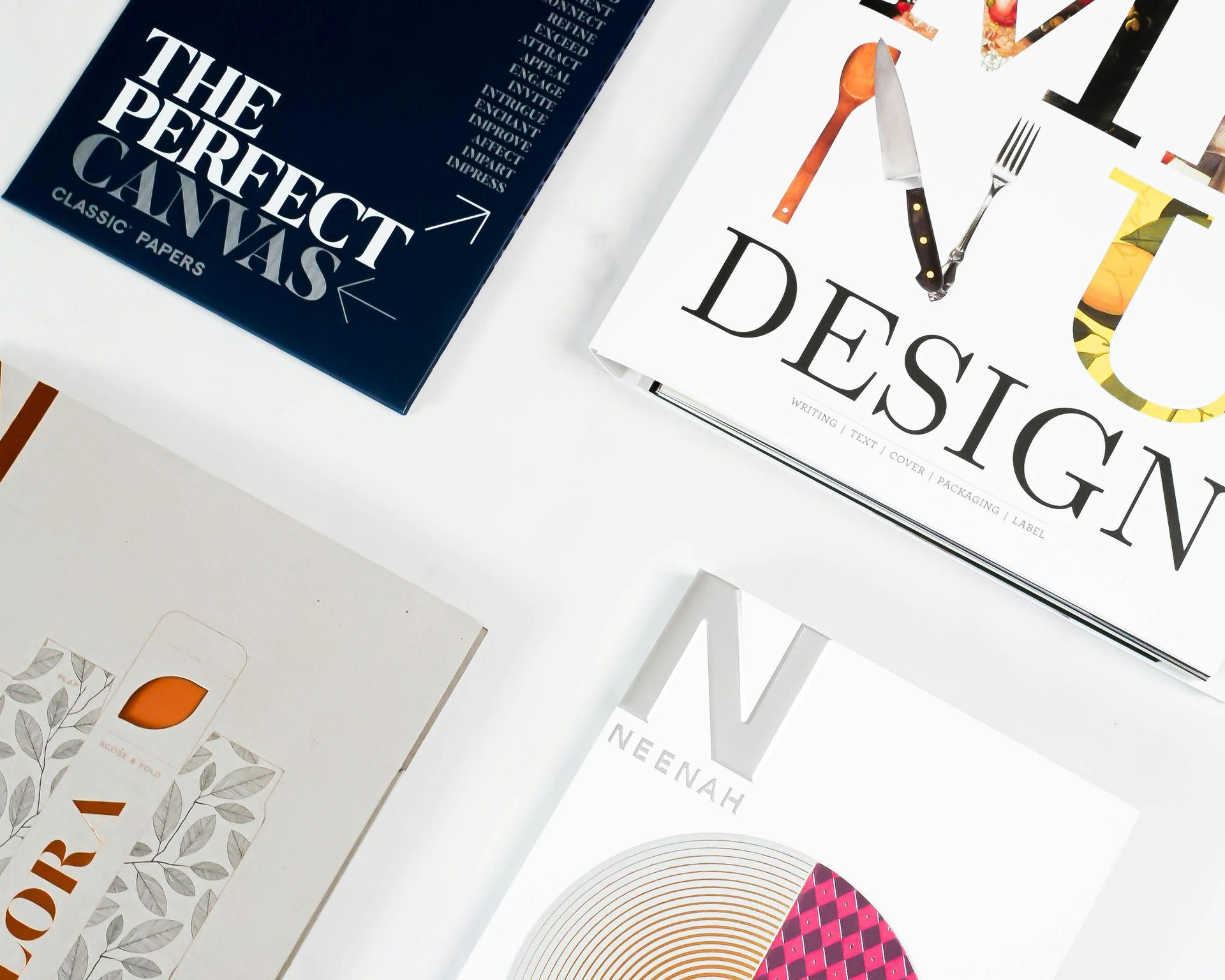 Una pila di libri colorati di design e arte su una superficie bianca, tra cui titoli come 