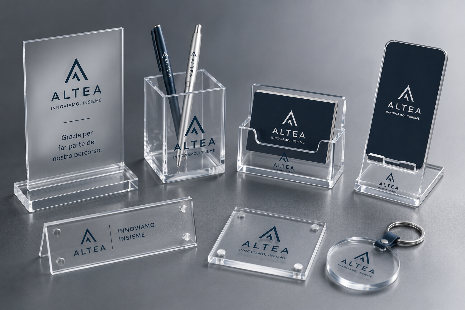 Accessori da scrivania in acrilico trasparente con logo ALTEA inciso, tra cui portapenne, vassoi, supporti per carte e portachiavi.