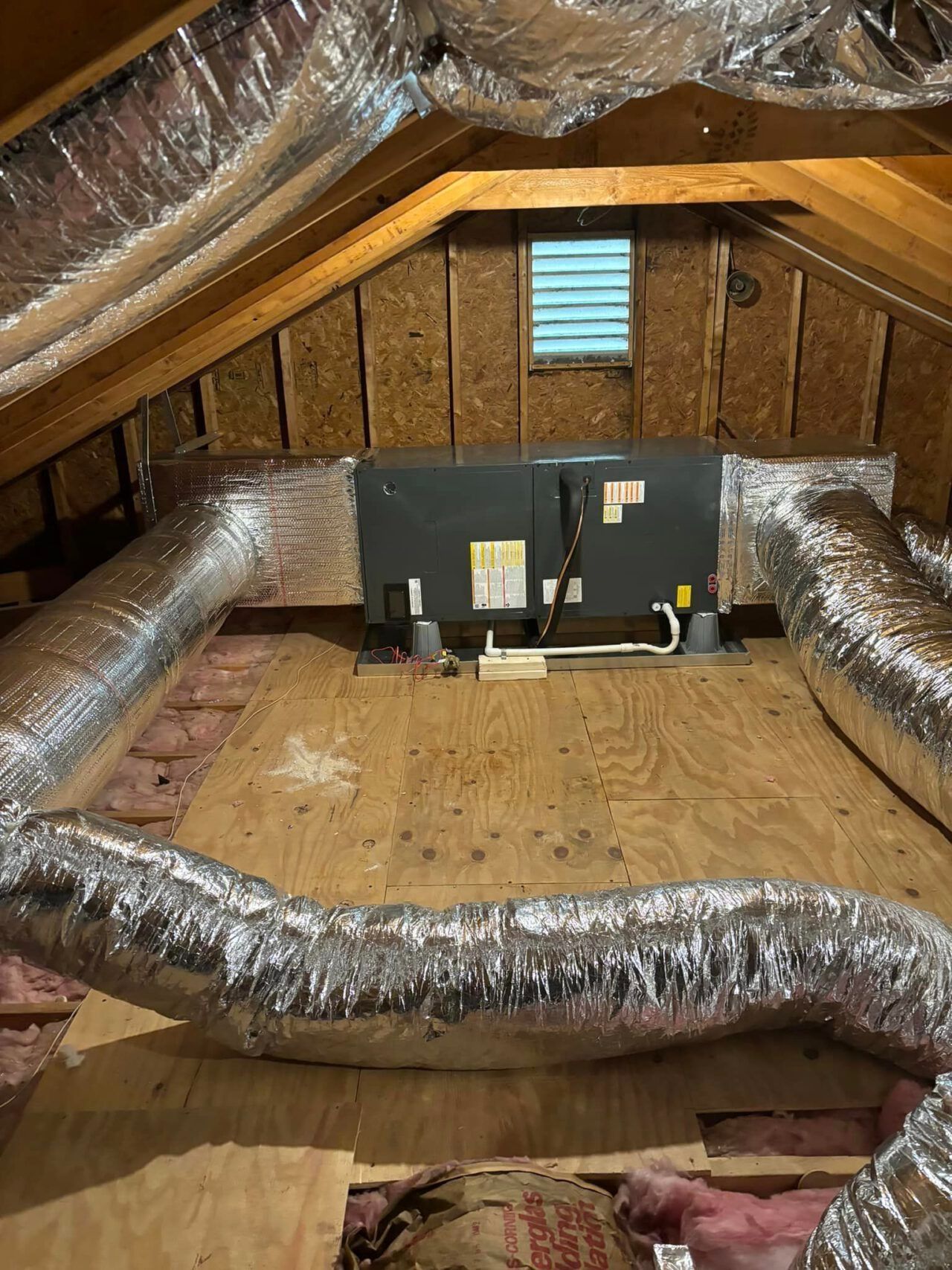 Attic workspace with duct insulation, two monitors, and exposed wood walls and floor