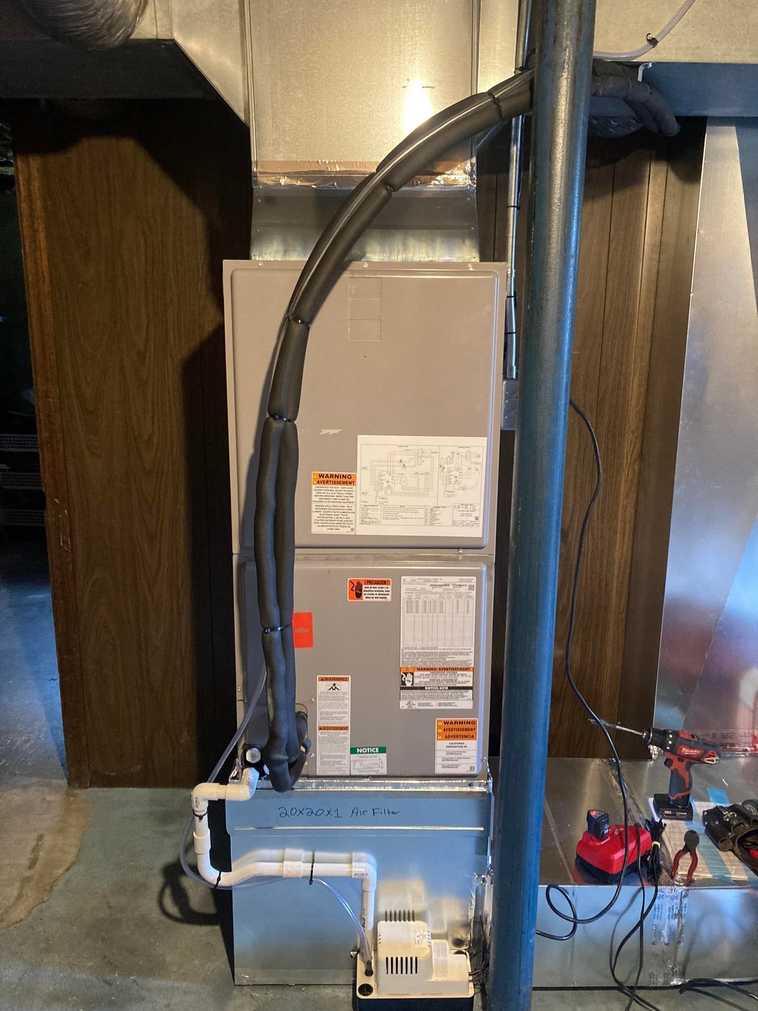 HVAC furnace in a basement, with ductwork and exposed wiring around it.