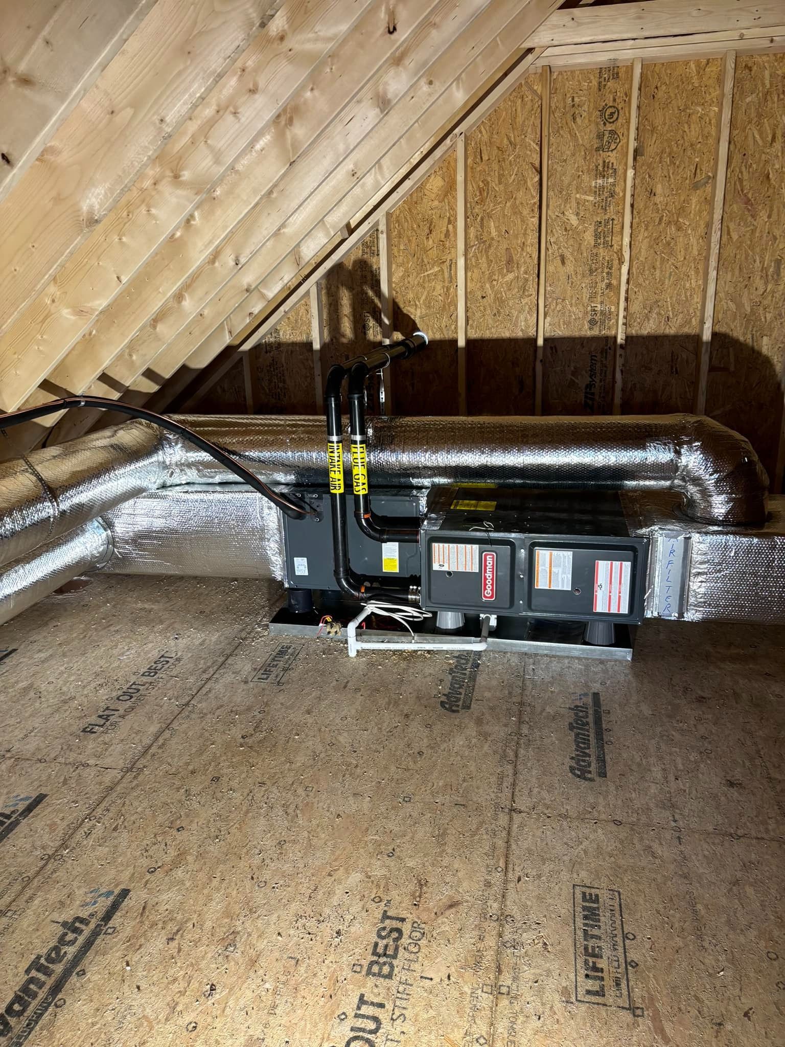 Attic HVAC unit with ductwork and insulation under a sloped roof