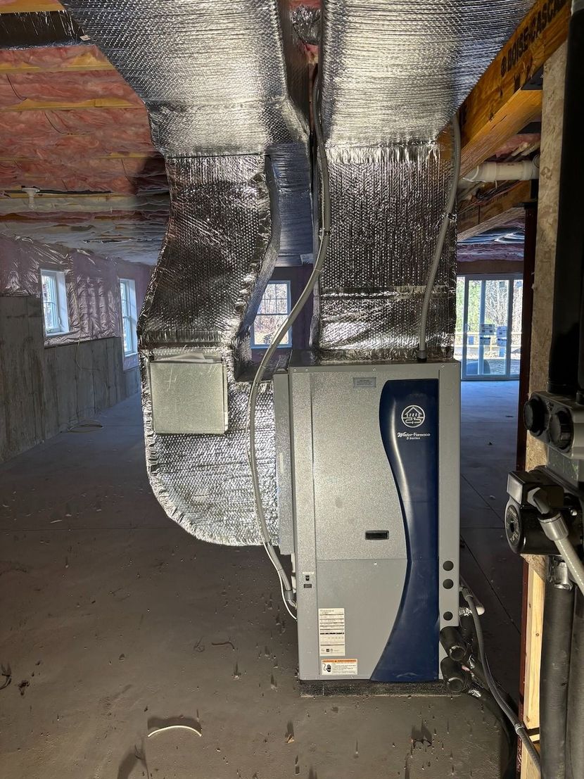 Basement HVAC unit with silver ductwork and blue paneling in a partially finished room.