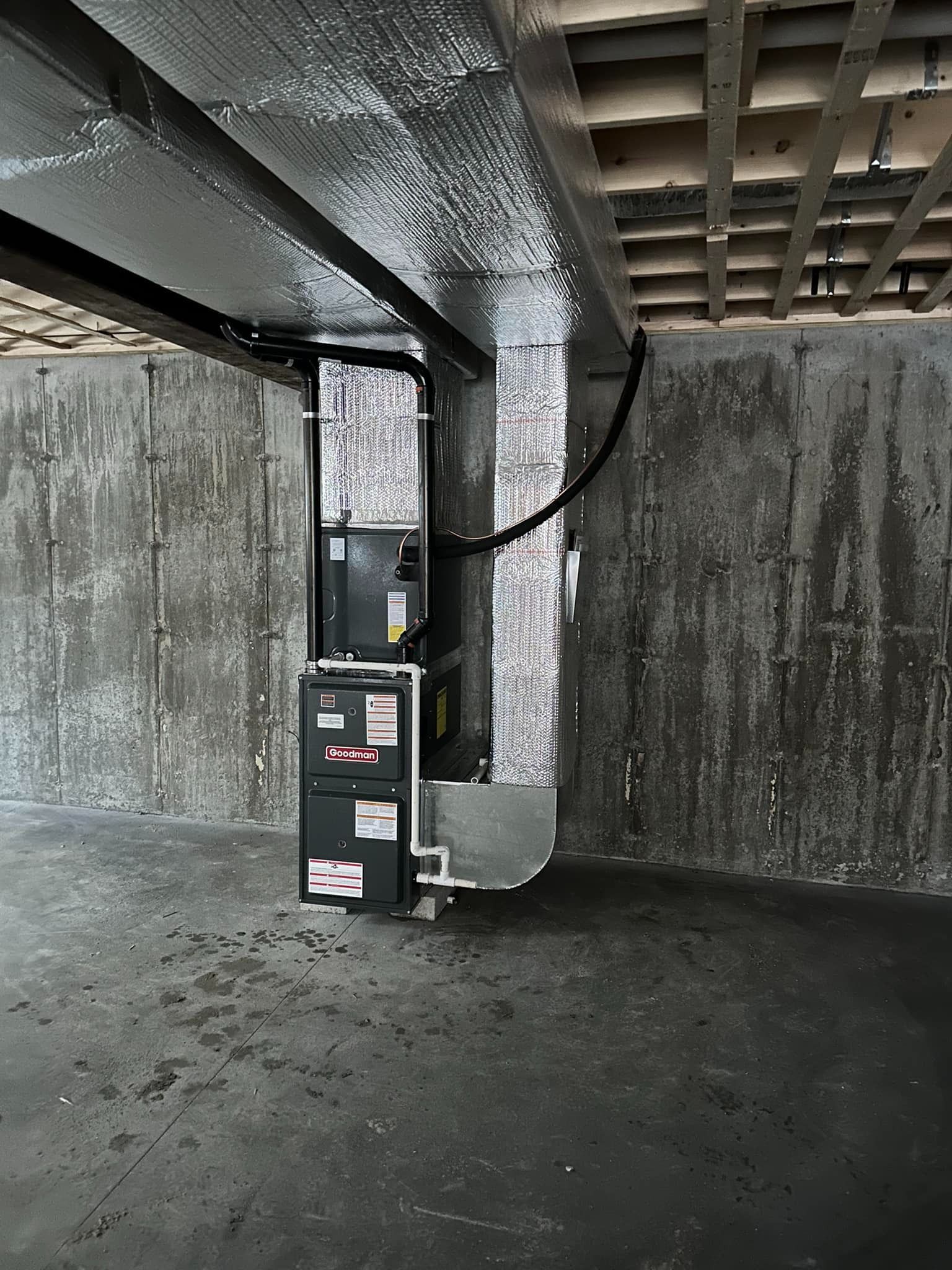 Dim industrial basement with concrete walls, exposed ceiling, and a black equipment cabinet near the center.