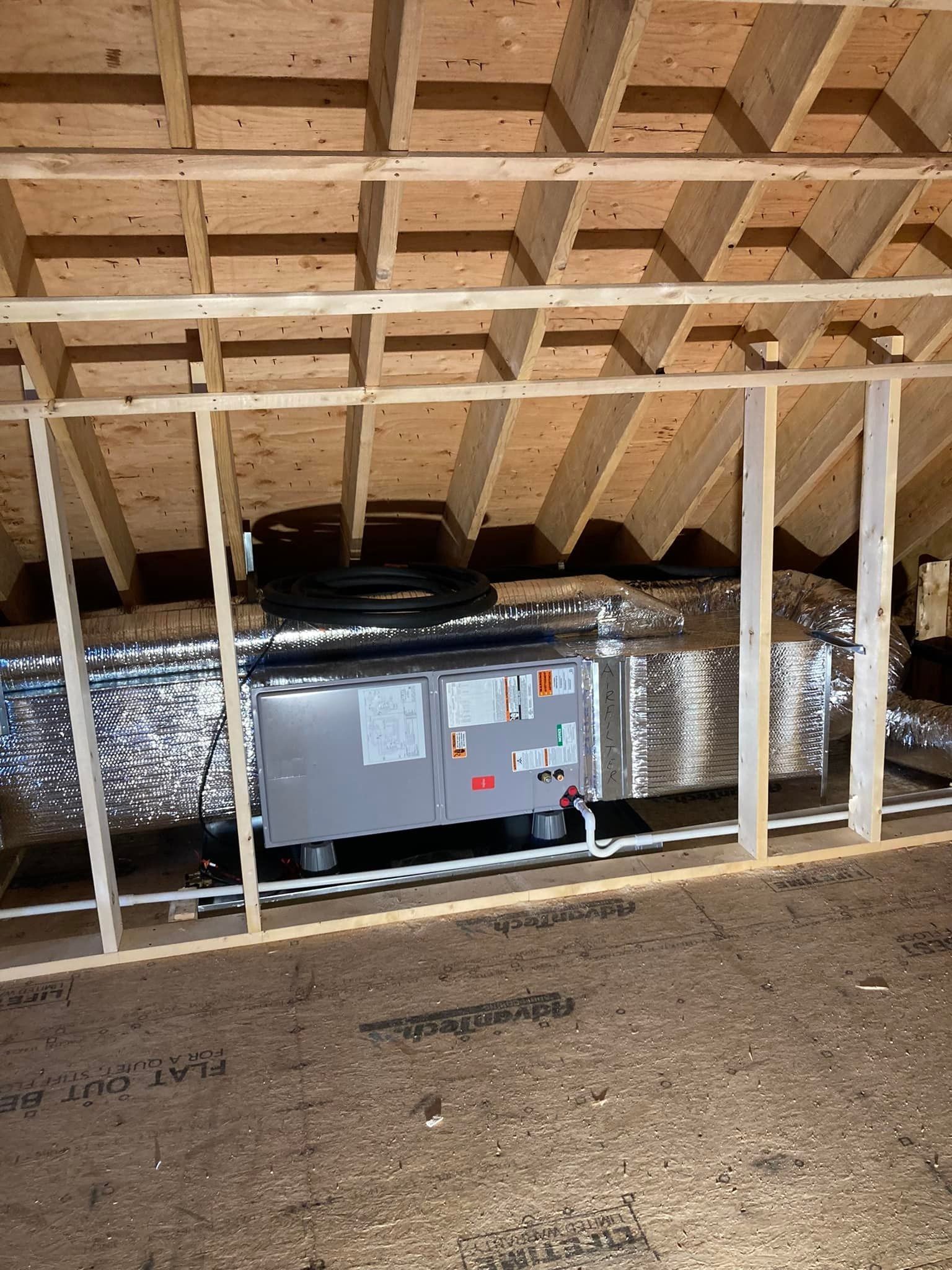 Attic HVAC unit with insulated ductwork and exposed wooden framing