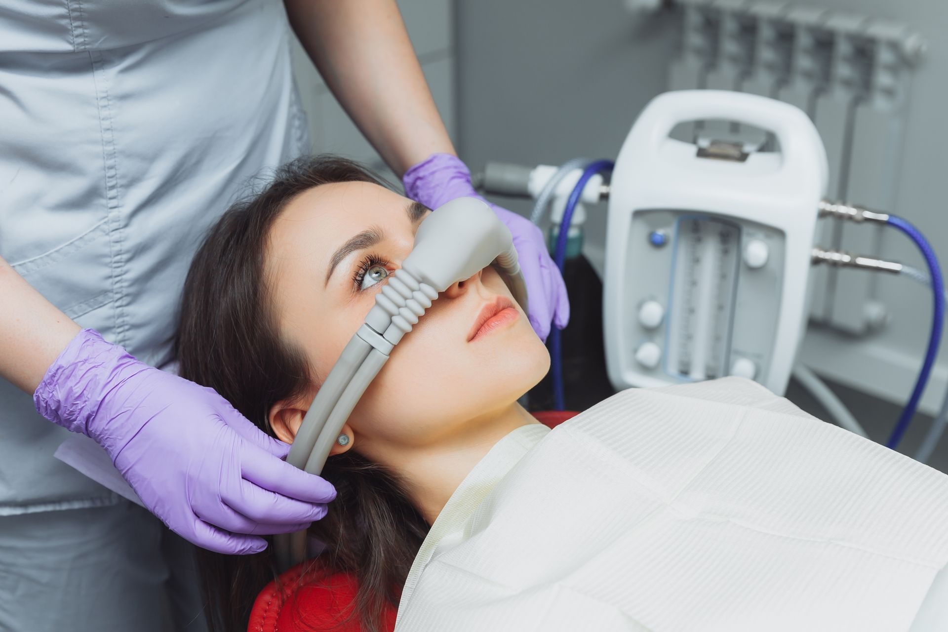 Relax during your root canals and extractions with sedation options from our holistic dentist in Morgantown WV A woman is laying in a dental chair with an oxygen mask on her nose.