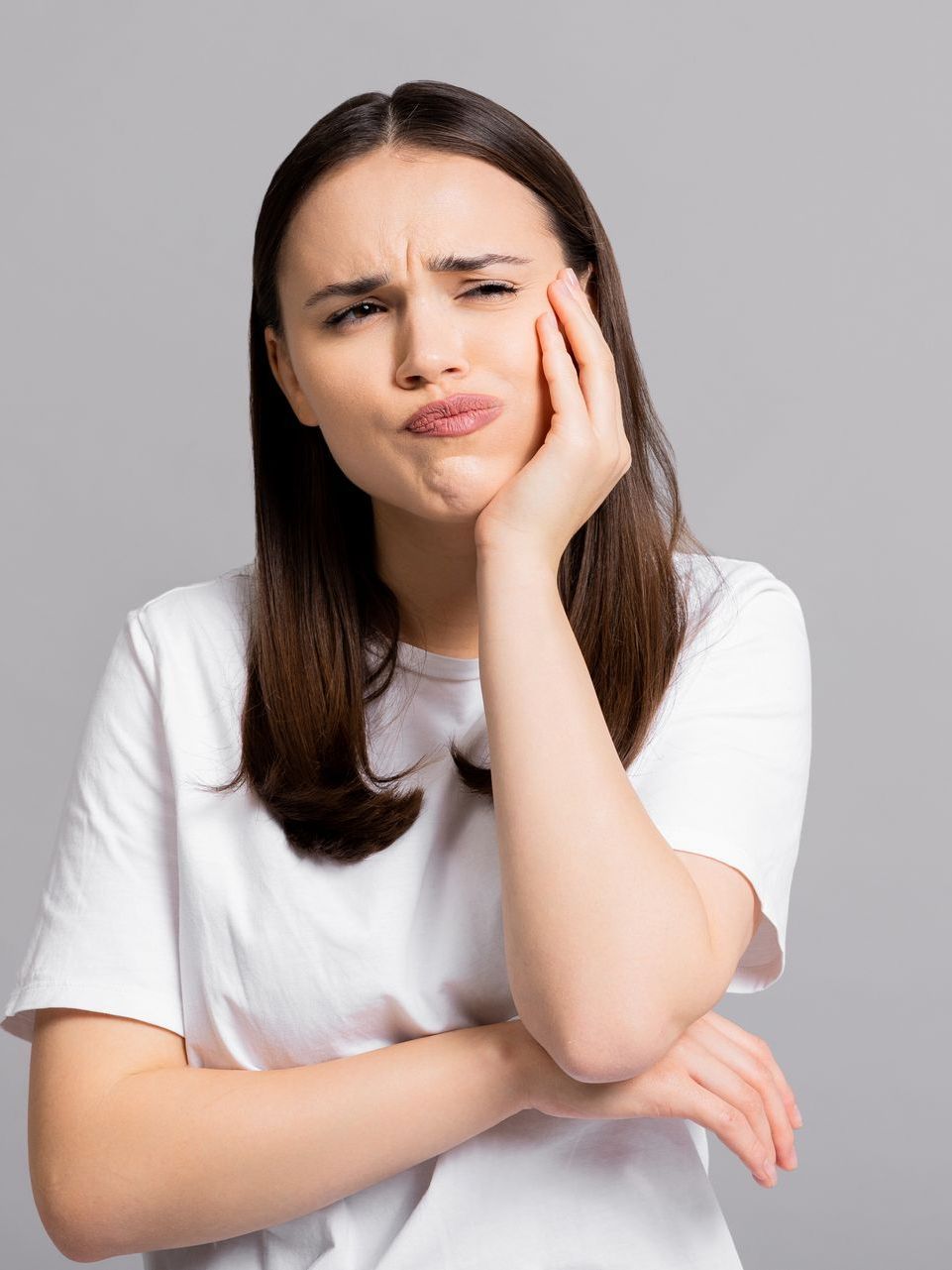 Get wisdom teeth extractions and more with sedation dentistry in Morgantown WV A woman in a white t-shirt is holding her hand to her face.