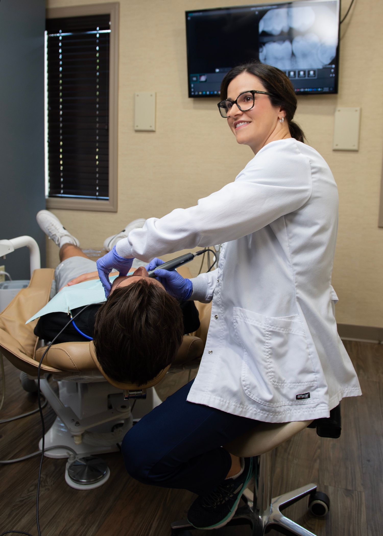 Intra Oral Cameras at Our Natural Dentist in Morgantown WV A dentist is examining a patient 's teeth in a dental office.