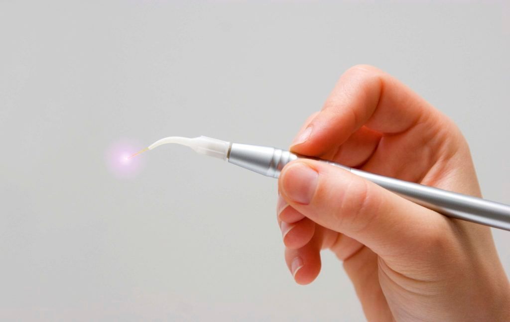 A person is holding a pen with a light coming out of it.