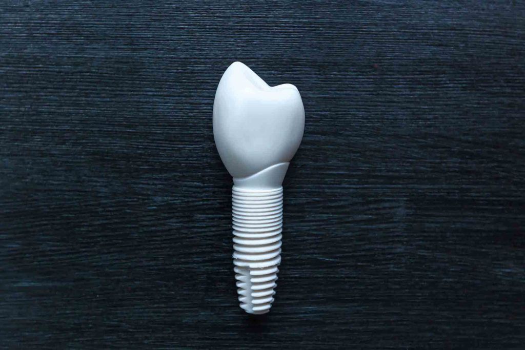 A dental implant is sitting on a black wooden table.