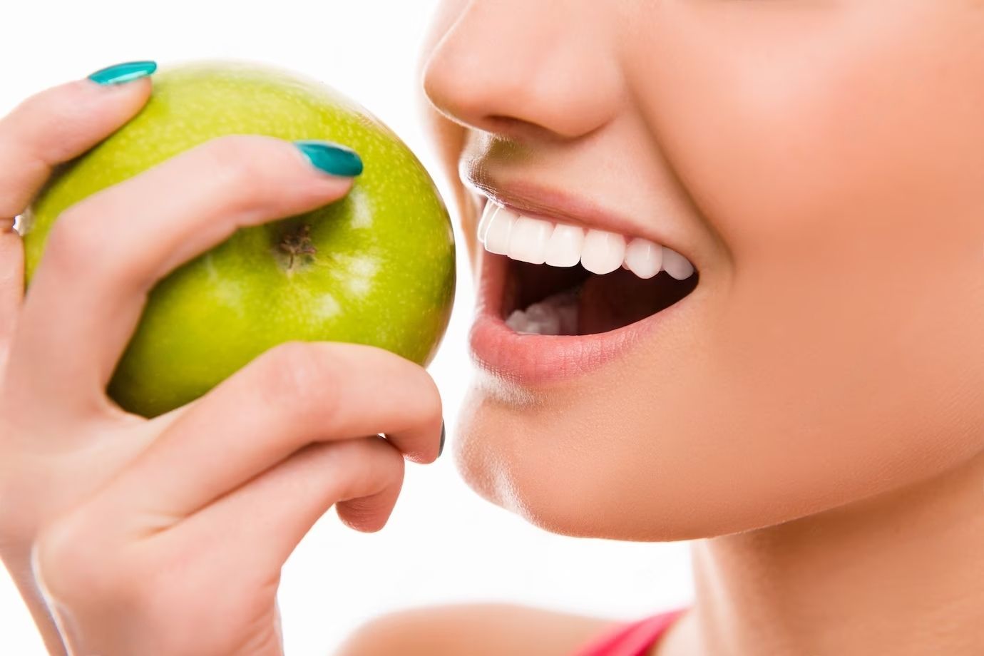 A woman is eating a green apple with her mouth open.