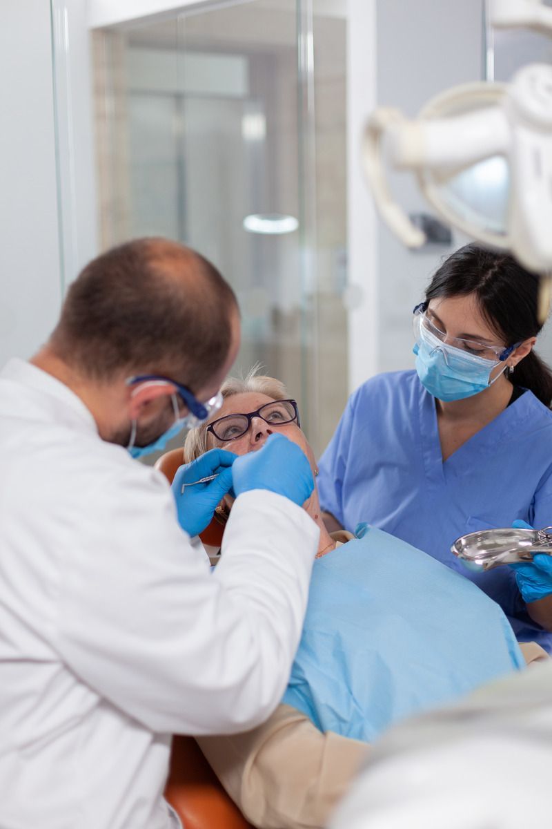 A dentist is examining a patient 's teeth in a dental office.
